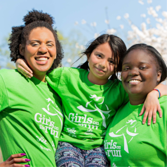 Two smiling Girls on the Run coaches holding participant